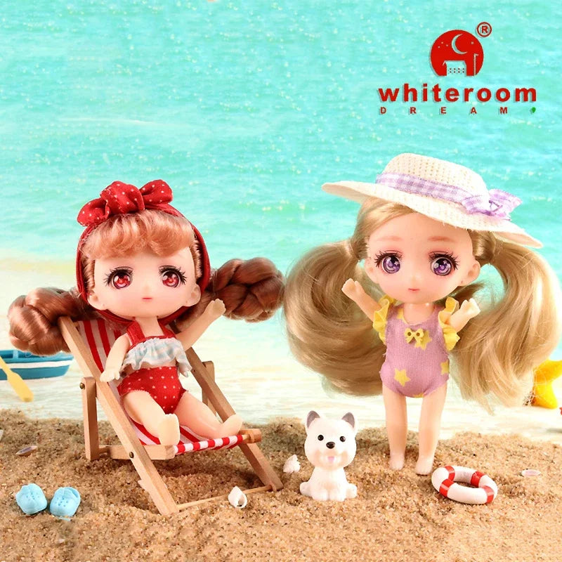 A white room dream doll with pink hair and a straw hat sitting on the sand next to a small white dog.