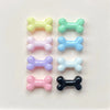 A collection of six small, bone-shaped resin charms in various pastel colors including yellow, green, pink, blue, purple, and