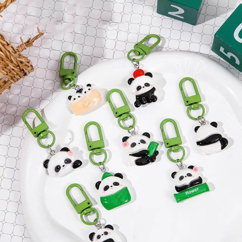 A collection of adorable panda keychains with green metal clasps displayed on a white plate.
