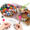 A collection of colorful silicone beads is displayed on a wooden board next to a hand, illustrating soft food-grade materials
