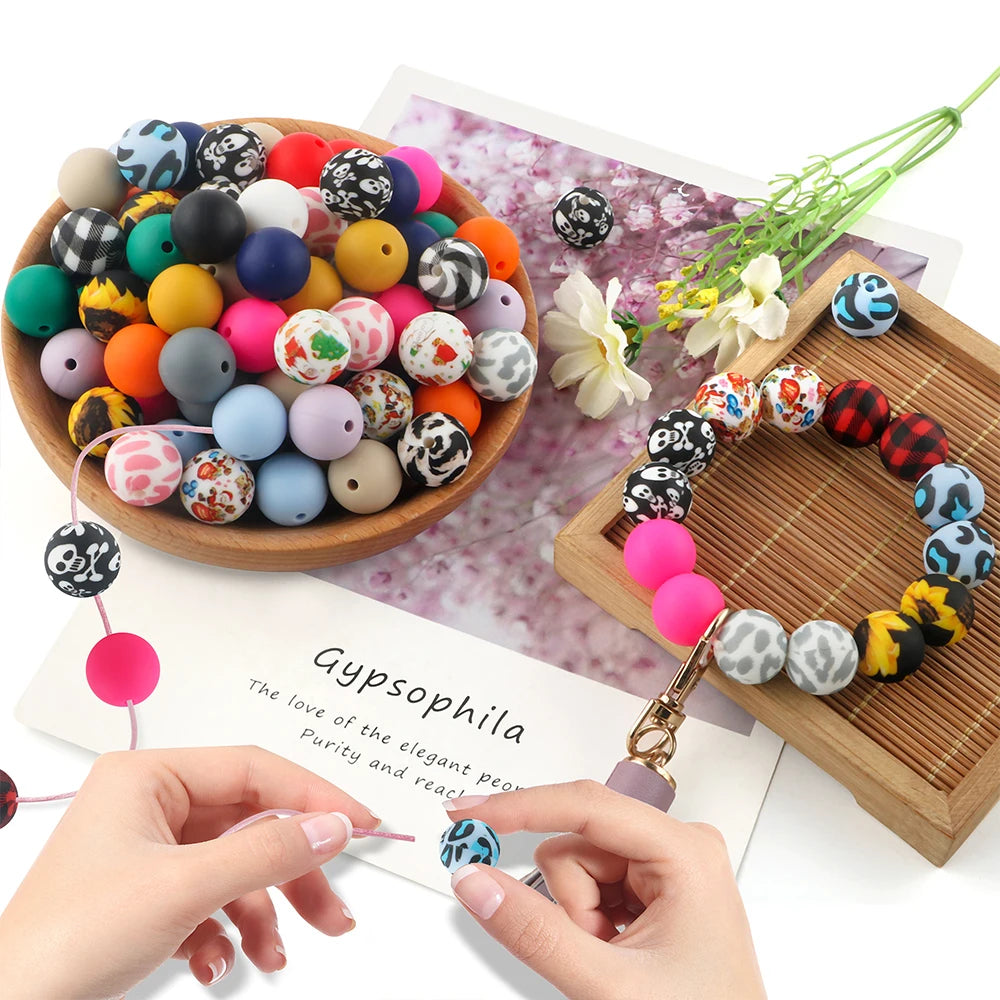 A collection of colorful silicone beads is displayed on a wooden board next to a hand, illustrating soft food-grade materials