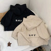 A beige kids hooded jacket with a black letter print on the chest, displayed on a white surface.