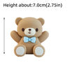 A light brown teddy bear cake topper with a blue bow and white paws.