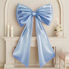 Oversized creamy white satin bow decoration displayed on a white mantelpiece.