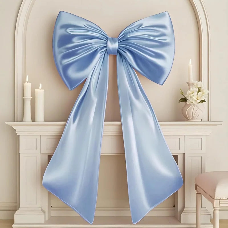 Oversized creamy white satin bow decoration displayed on a white mantelpiece.