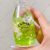 A hand holds a clear bottle filled with bright green liquid, labeled Chiboki Drink cup toy.