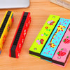 Five colorful wooden harmonica cases featuring cartoon animal designs laid on a wooden surface.
