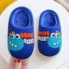 Pair of blue dinosaur plush slippers with fuzzy lining resting on a white plate.