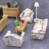 A pink floral mini sofa and pillow set for a dollhouse displayed on a gray carpet.