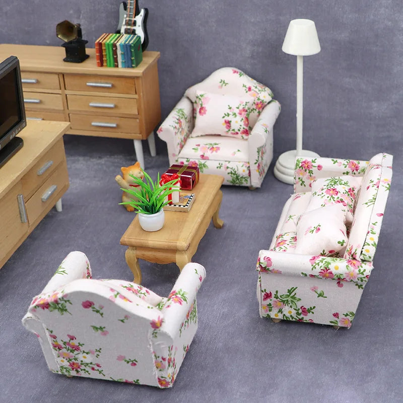 A pink floral mini sofa and pillow set for a dollhouse displayed on a gray carpet.