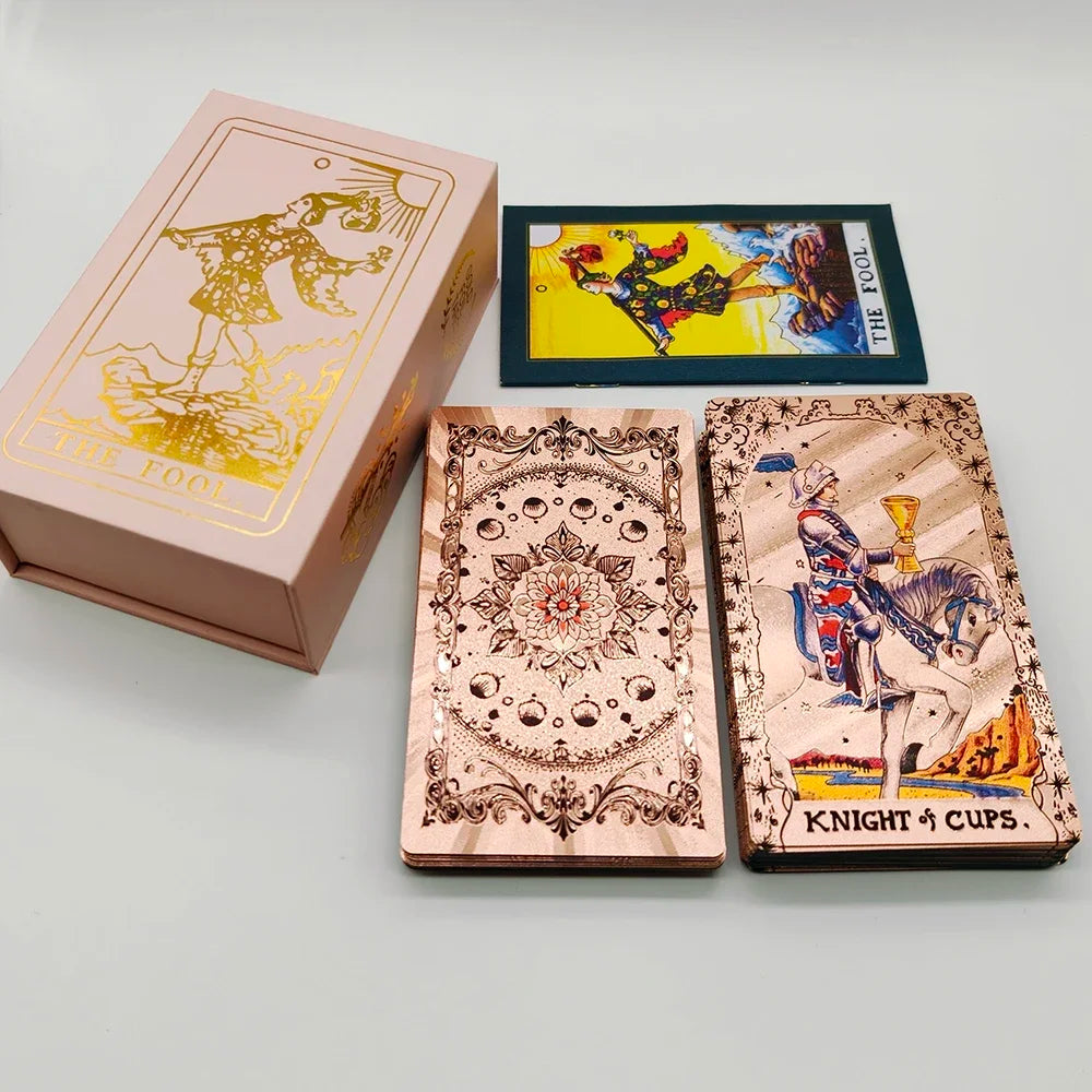A deck of gold foil tarot cards with a rose pink oracle finish, including a box and individual cards.