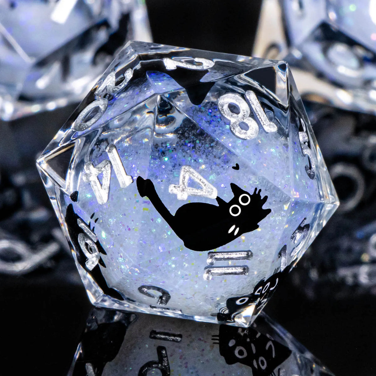 A clear, faceted resin die with a black silhouette of a cat on its surface.