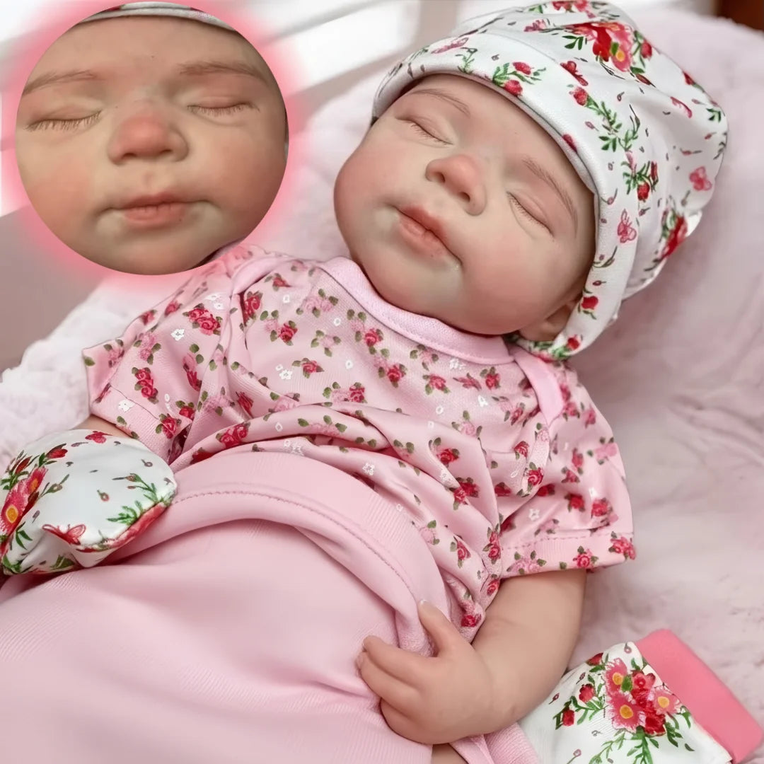 A lifelike 18-inch silicone reborn baby doll named Pascale with pink floral clothing lying on a pink surface.