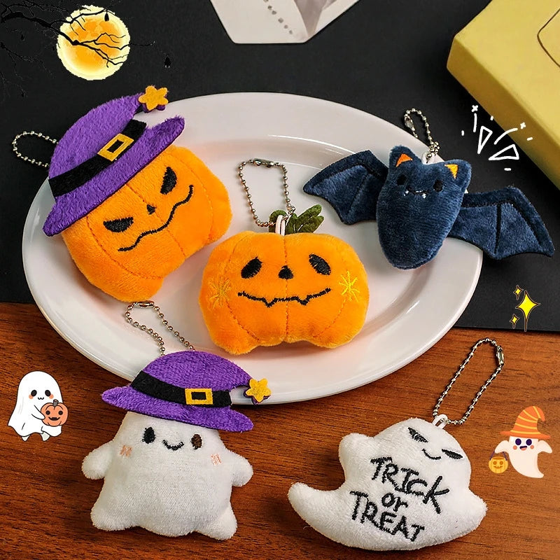 A set of Halloween plush keychains featuring a ghost, pumpkin, and bat charm on a white plate.