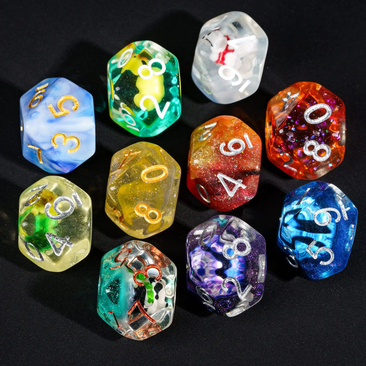 A collection of seven polyhedral resin dice in various colors and patterns arranged on a dark surface.