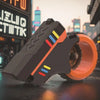 A close-up of a dark gray and orange 3D printed rotary finger slider fidget toy resting on a dark surface.