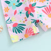 Pink baby rash guard swimsuit with a colorful floral print featuring green, pink, and yellow leaves and flowers.