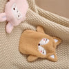 A light pink plush animal and a tan plush animal resting on a beige knitted fabric.