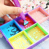 A hand is using a purple diamond painting pen to apply red resin dots into various colored compartments inside a multi-sectio
