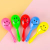 A collection of seven brightly colored mini maracas shaker toys in pink, green, red, blue, and yellow against a light backgro