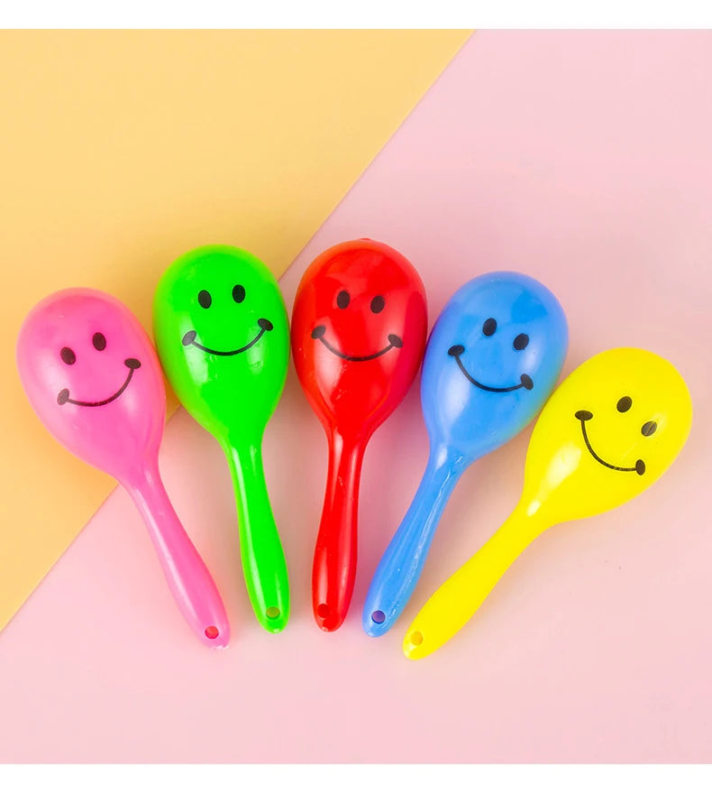 A collection of seven brightly colored mini maracas shaker toys in pink, green, red, blue, and yellow against a light backgro