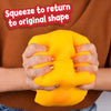 Hands squeezing a yellow soft moldable cheese stress relief toy against a brown sweater.