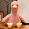 A pink realistic call duck plush toy with a yellow beak sitting on a wooden surface.