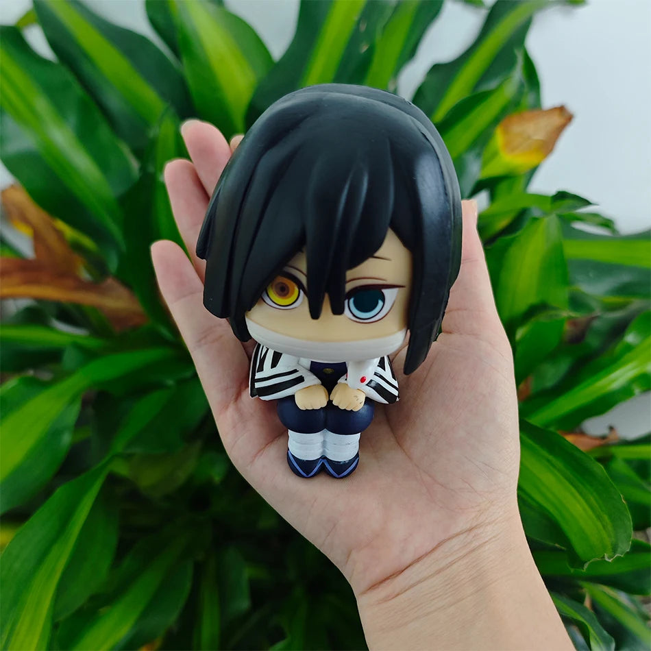 A set of four Demon Slayer anime action figures, including Tanjirou, Nezuko, Giyuu, and Mitsuri, is held in a hand against a 