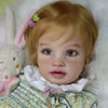 A realistic reborn baby doll kit named Pippa with blonde hair and light blue eyes, wearing a floral top.