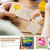 Hand holding small natural wood squares with a yellow flower design and a rainbow, used for DIY crafts.
