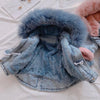 A light blue denim jacket with a fluffy faux fur collar and lining is displayed on a white surface.