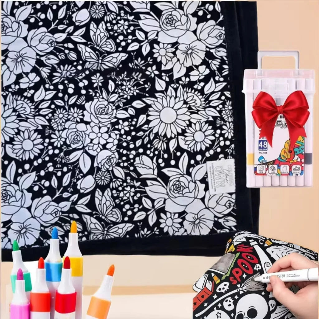 A black and white floral pattern blanket with a pink marker set and other art supplies displayed on a light background.