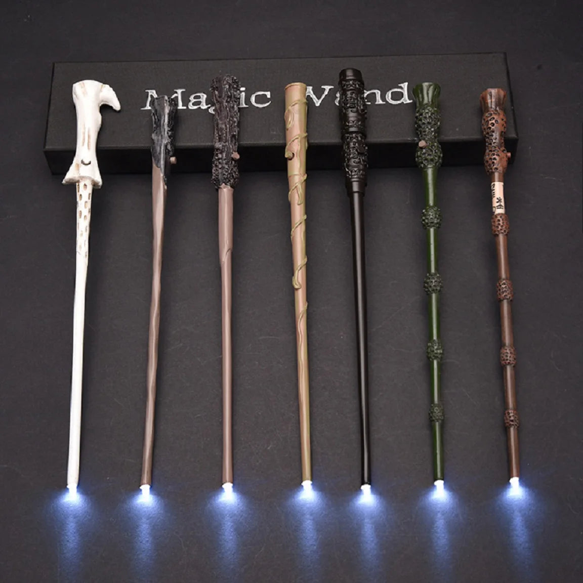A set of five LED light-up magic wands displayed in a black box on a dark surface.