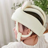 A child is wearing a white toddler safety helmet and head cushion designed for crawling protection.