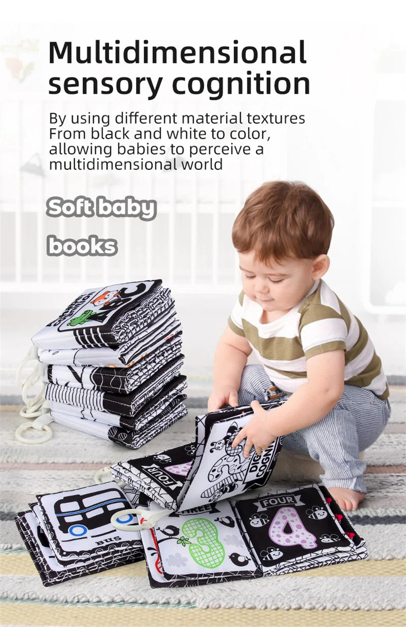 A baby is looking at a stack of black and white cloth books designed for multidimensional sensory cognition.