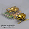 A set of three gold-colored wind-up insect toys, including a ladybug, bee, and beetle, packaged in clear plastic.