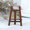 A small, rustic wooden artist easel used as a miniature prop for a dollhouse display.
