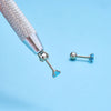A silver precision tool with a fine tip and a small blue gemstone is shown against a light blue background.