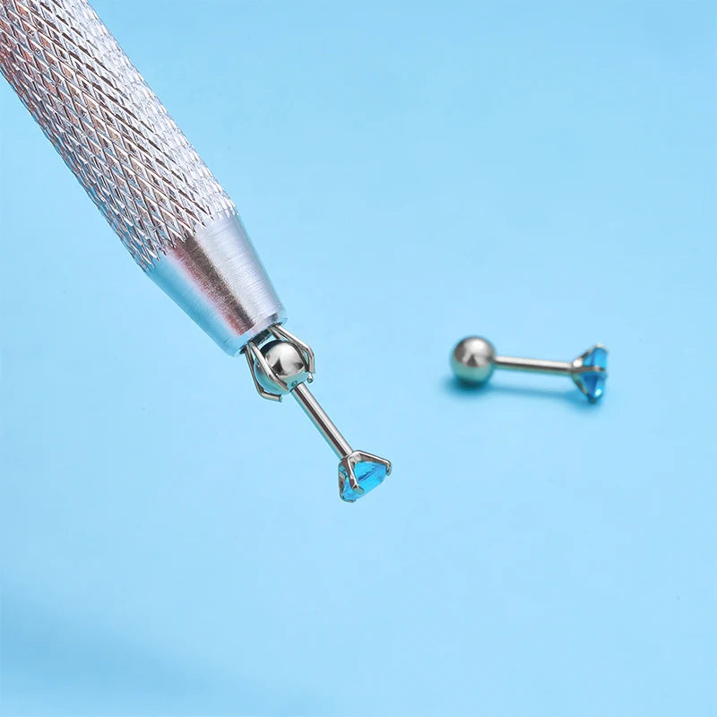 A silver precision tool with a fine point and a small blue gemstone is shown against a light blue background.