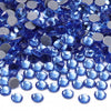 A close-up view of various blue and silver glass crystal rhinestones scattered on a white background.