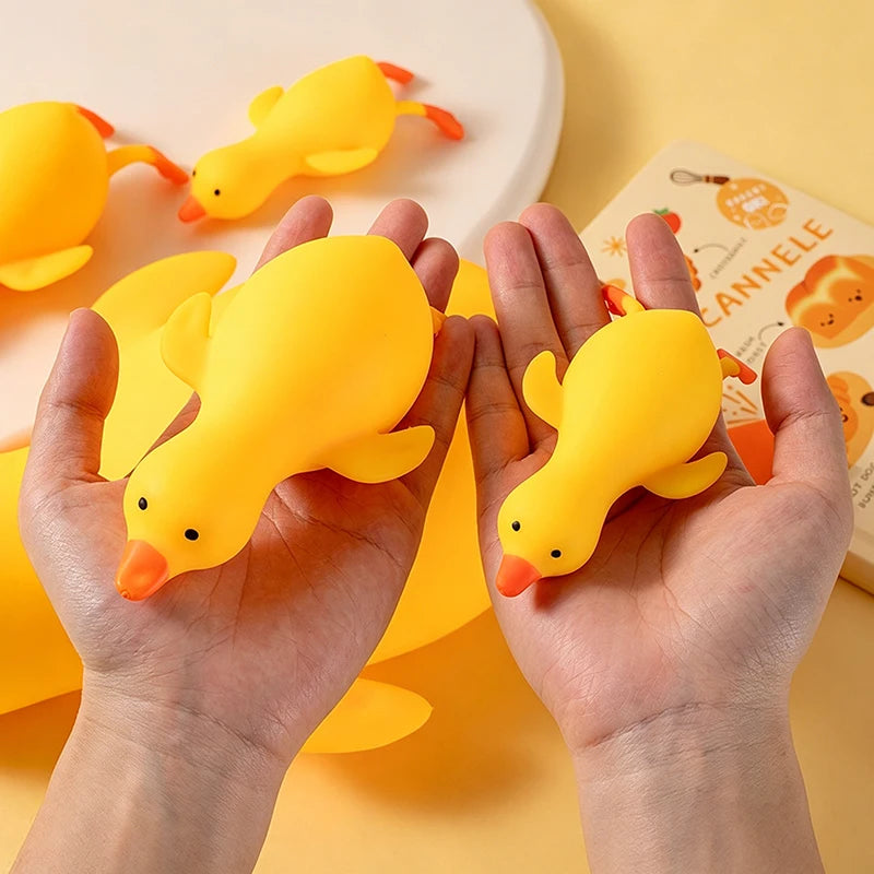 Hands holding a yellow squishy duck stress relief toy against a light yellow background.