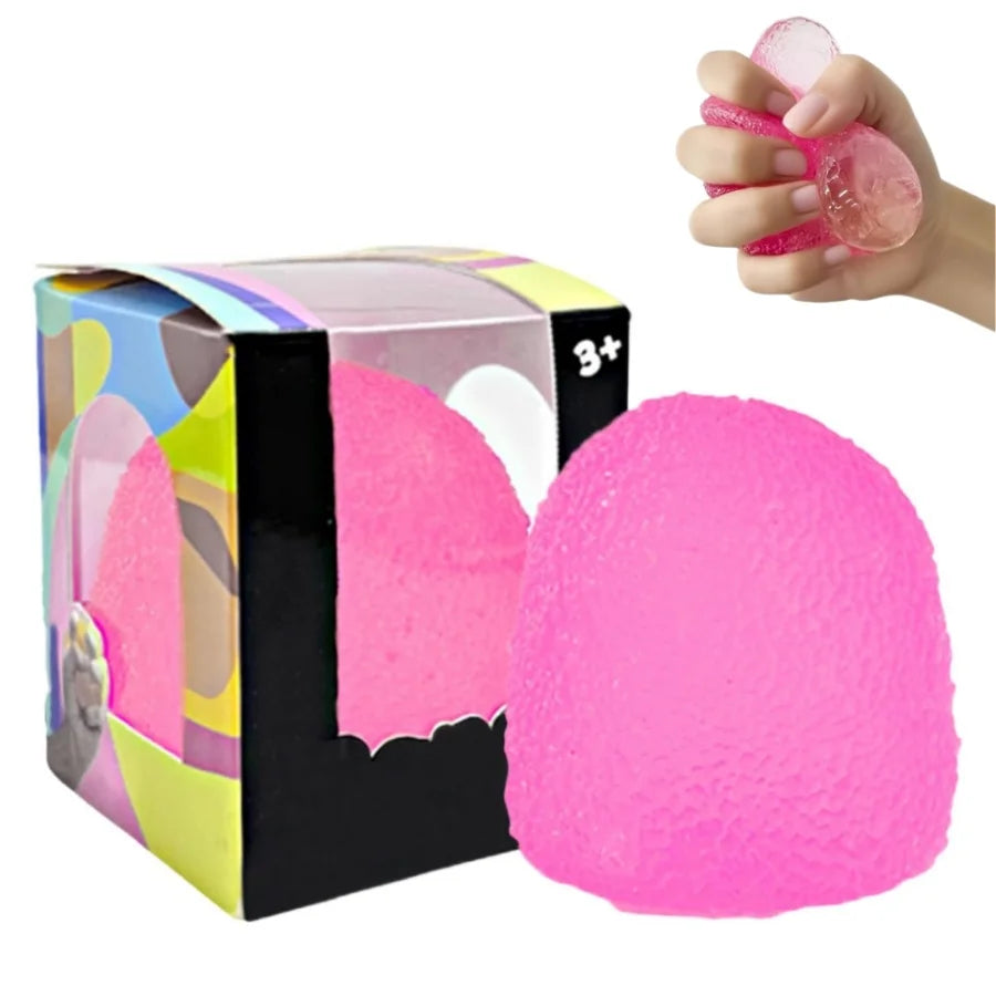 A hand is squeezing a bright pink slow rise squishy stress ball, next to its packaging box.