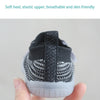 A close-up shot of a pair of black and gray breathable mesh toddler walking shoes being held by a hand.