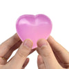 Eine Hand drückt einen rosa herzförmigen Stressball.