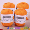 Four balls of orange cotton knitting yarn labeled Golden Sun for crochet and handmade projects
