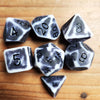 A set of polyhedral dice, including a d4, d6, d8, and d10, resting on a wooden surface.