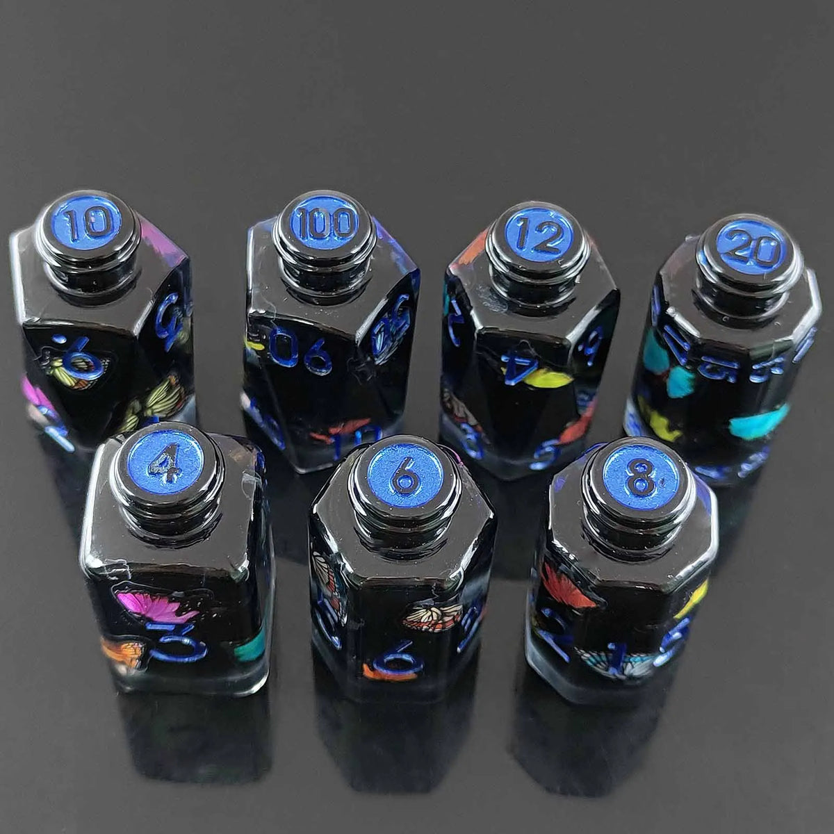 A set of seven floral resin potion bottle polyhedral dice, numbered 4 through 10 and 12, displayed on a dark surface.