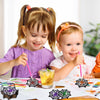 Two young girls are decorating a DIY diamond art coaster set with spider web designs on paper.