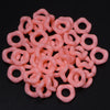 A pile of pink acrylic doughnut spacer beads for jewelry making