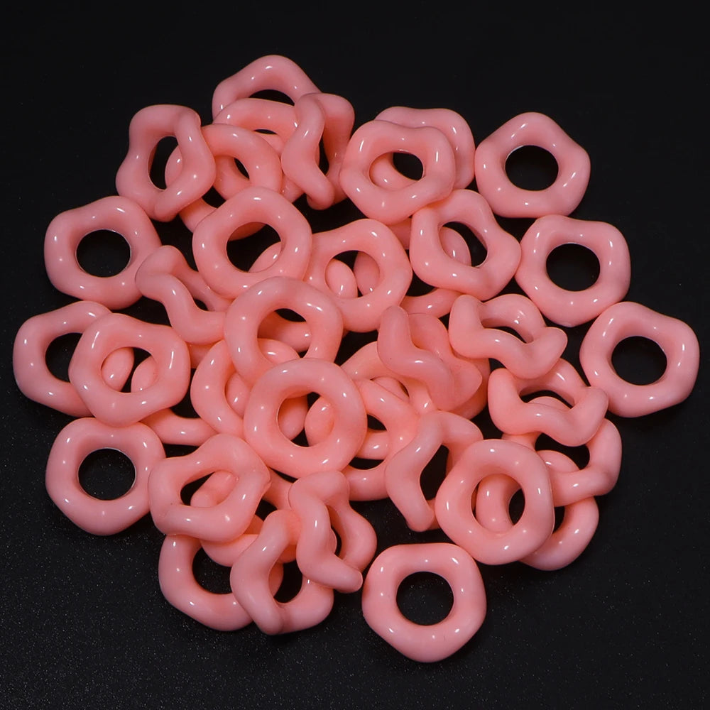 A pile of pink acrylic doughnut spacer beads for jewelry making